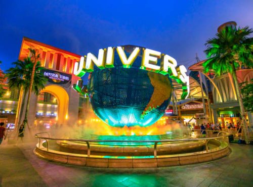 Singapore - May 2, 2018: Universal Studios world globe in green light, with tourists visiting this Hollywood movie theme park in Sentosa island.